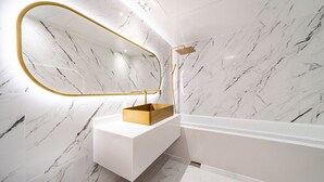 A bathroom with a marble wall, a gold-framed mirror, a white sink, and a gold showerhead. - Insta Hotel - Main Branch (Suwon)