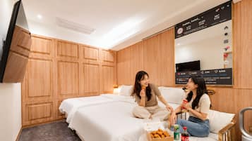 A hotel room with a bed, a small table with snacks and drinks, and a wall-mounted TV.