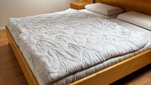 Un dormitorio con techo inclinado, tragaluz, cama con colchón acolchado y mesita de noche.