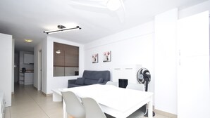 Een moderne keuken met witte kasten, een grijze bank en een eettafel met stoelen.