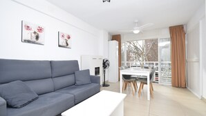 Een moderne woonkamer met een grijze bank, een witte salontafel, en een eetgedeelte met een witte tafel en stoelen.