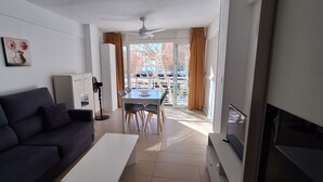 Een moderne woonkamer met een bank, een salontafel, een televisie en een eethoek met een tafel en stoelen.
