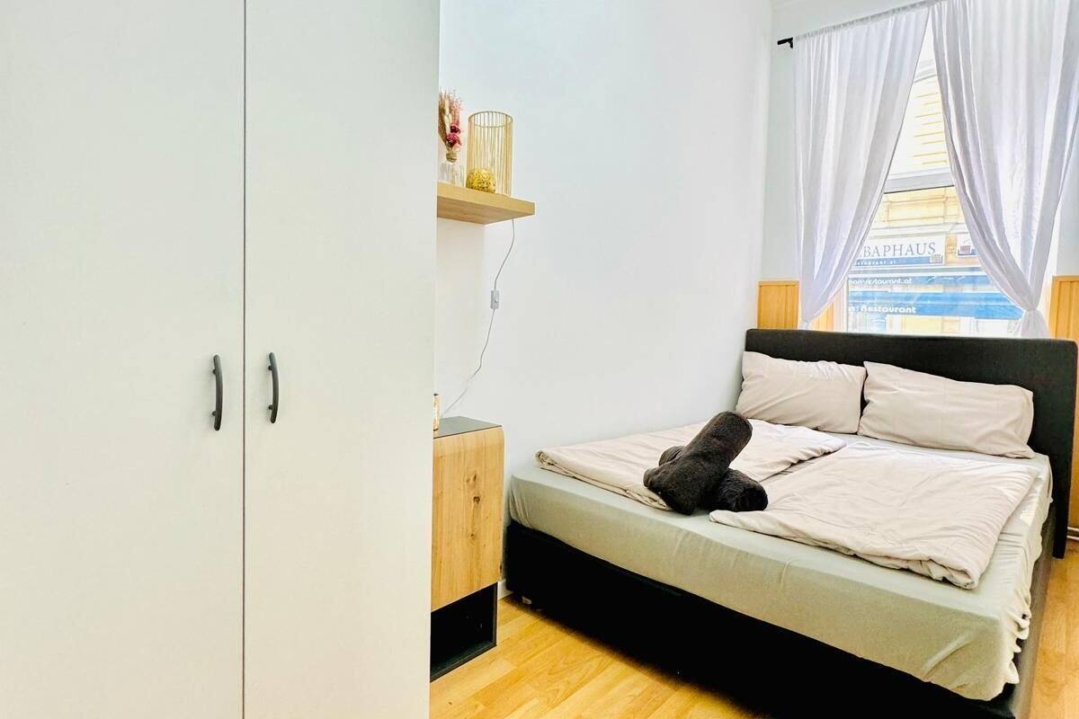 A bedroom with a bed, a wardrobe, and a window with curtains.