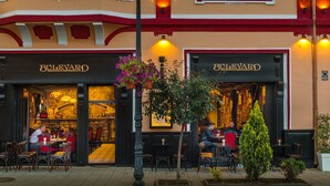 The exterior of a restaurant with outdoor seating, a red and beige facade, and a sign reading "Bulevard Romanian Restaurant." - Hotel Boutique Bulevard (Sighisoara)