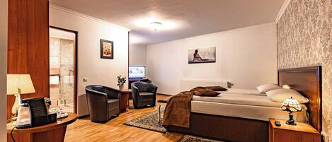 Una habitación de hotel con cama, escritorio, silla, televisor y lámpara.