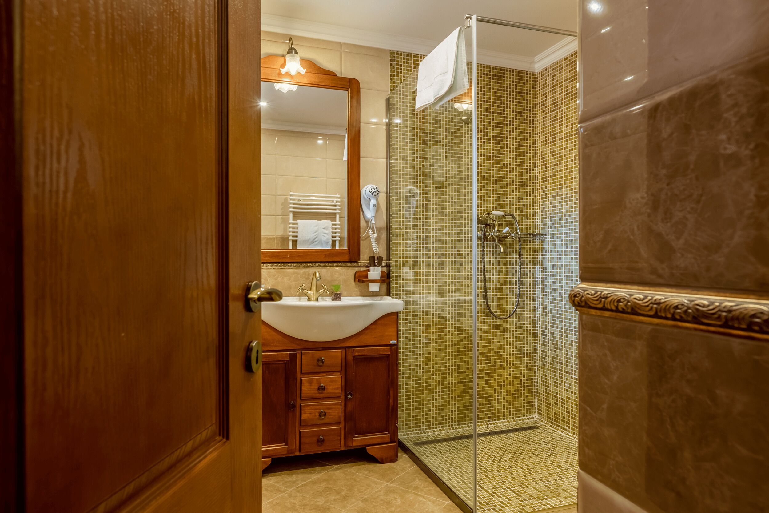 Un baño con tocador de madera, cabina de ducha con mampara de vidrio y pared de azulejos.
