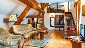 A cozy living room with a wooden staircase, a sofa set, and a television. - Hotel Boutique Bulevard (Sighisoara)