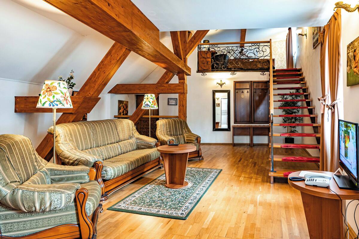 Una sala de estar acogedora con una escalera de madera, un conjunto de sofás y un televisor.