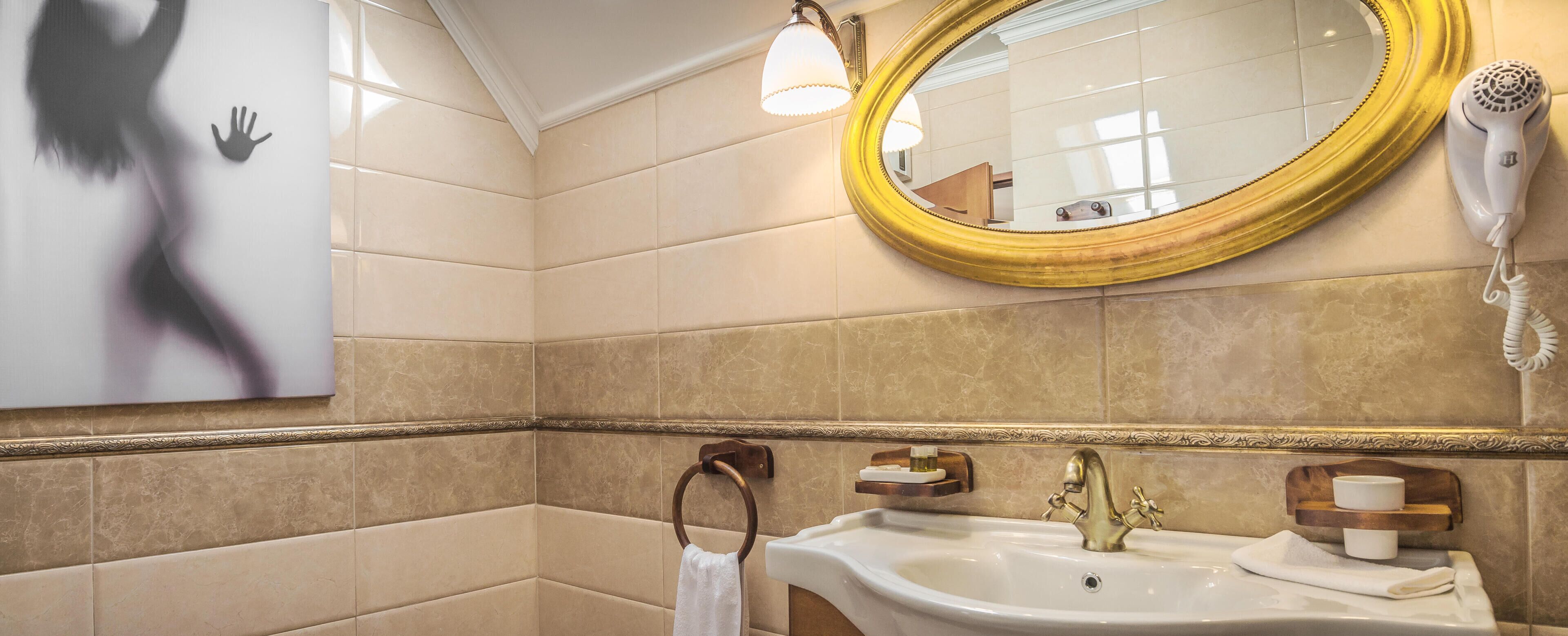 A bathroom with a large mirror, a sink, a towel ring, and a hairdryer.