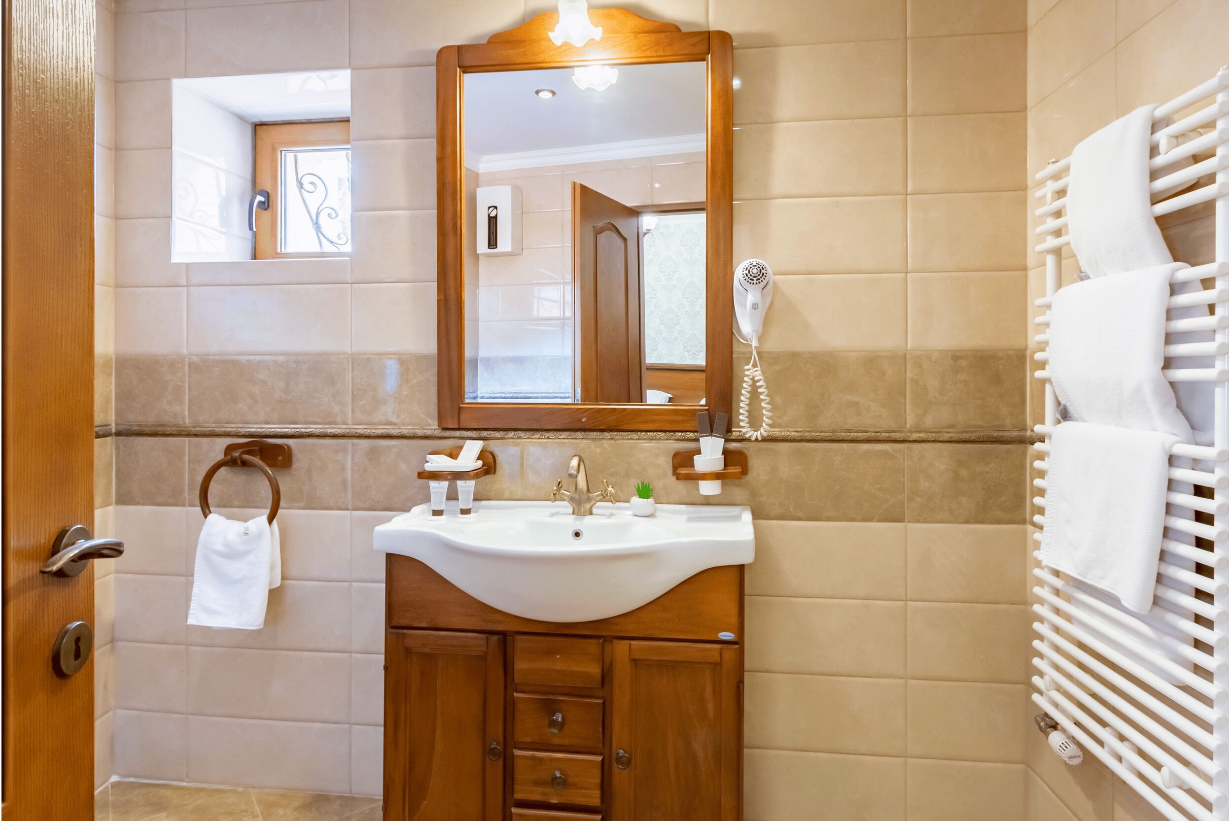 A bathroom with a wooden vanity, a sink, a mirror, a hairdryer, and a towel rack.