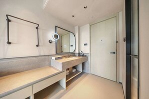 Un baño moderno con un espejo grande, un tocador con lavamanos y un perchero para toallas.