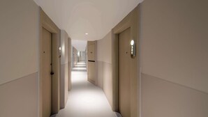 A long, narrow hallway with doors on both sides, leading to a bright room at the end. - The Yume Hotel (Nanjing)
