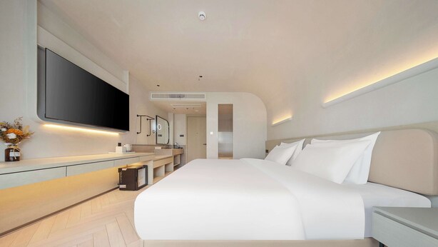 A modern bedroom with a large bed, a flat-screen TV mounted on the wall, and a minimalist design. - The Yume Hotel (Nanjing)