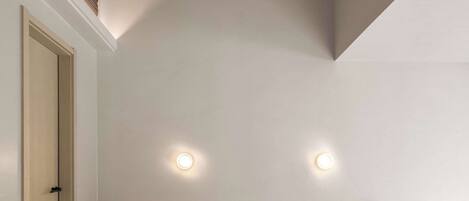 Un baño moderno con un banco blanco y rojo, un lavamanos redondo e iluminación empotrada en el techo.