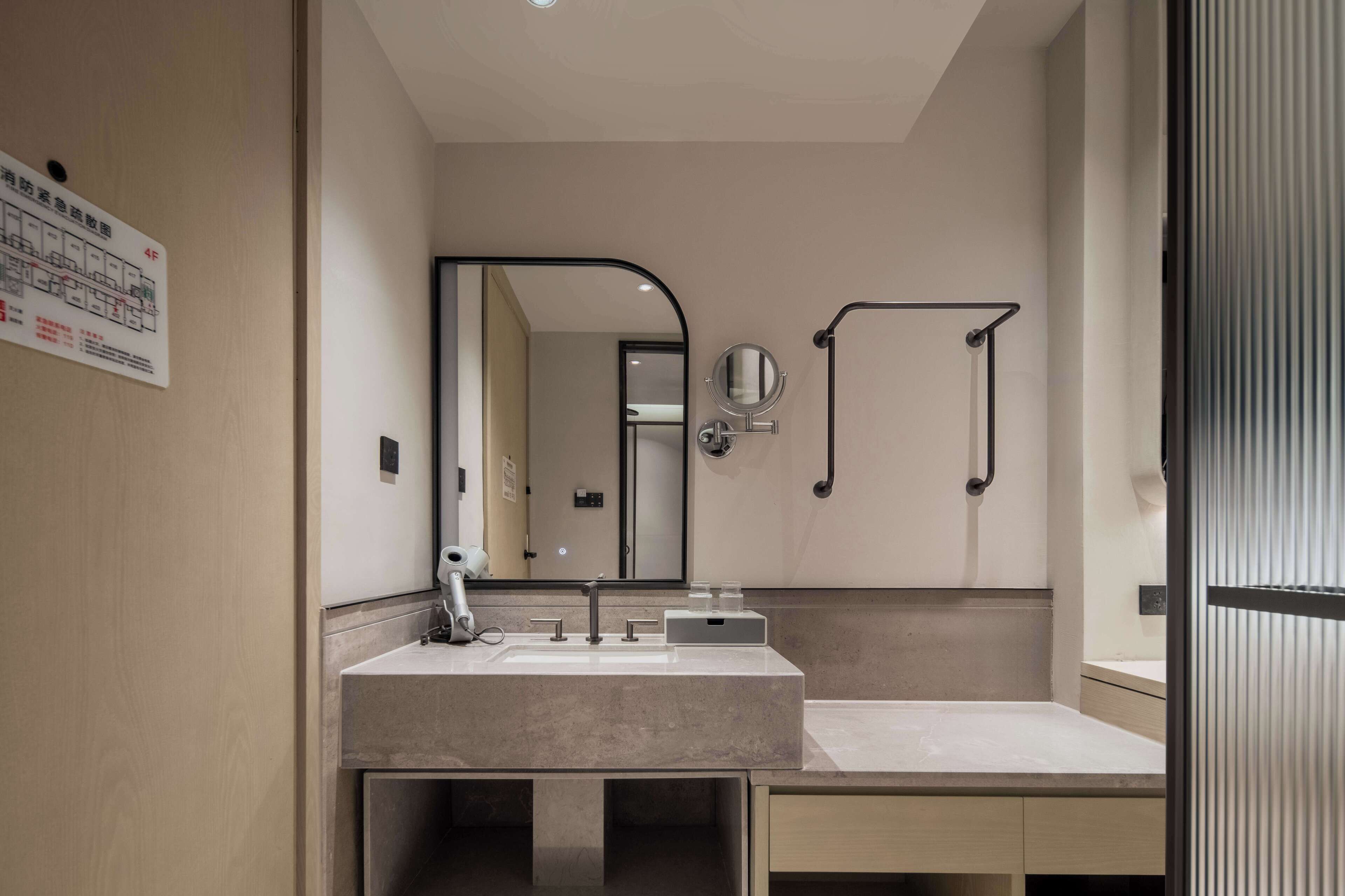 Un baño moderno con un espejo grande, un lavamanos y un perchero para toallas.