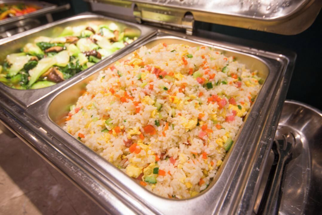 A buffet with various dishes including fried rice and stir-fried vegetables.
