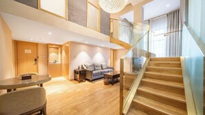 A modern hotel room with a wooden staircase, a glass railing, a sofa, a coffee table, and a dining table. - World Hotel Hexie Plaza branch (Jinan)
