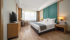 A hotel room with a bed, a desk, a television, and a nightstand. - World Hotel Hexie Plaza branch (Jinan)