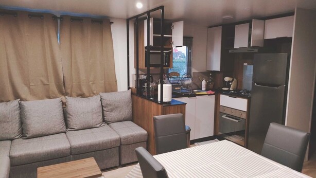 Un espace de vie compact comprenant un canapé, une table à manger et une kitchenette.