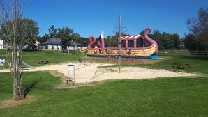 Une aire de jeux avec un toboggan, des balançoires et une structure d’escalade.