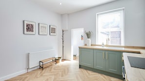 A modern kitchen with a herringbone floor, a white radiator, and a window with blinds. - Host Stay Mayfield (Harrogate)