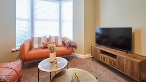 A living room with a sofa, a coffee table, and a TV on a wooden stand. - Host Stay Mayfield (Harrogate)