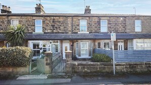 A row of terraced houses with stone facades, a gated entrance, and a 'Disc Zone' sign indicating parking restrictions. - Host Stay Mayfield (Harrogate)