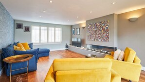 A modern living room with a blue sofa, yellow armchair, and a small table with a teddy bear. - Host Stay Chestnut Close (Saltburn-by-the-Sea)