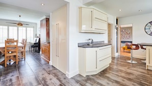 A modern kitchen with a dining area, wooden flooring, and a view of the living room. - Host Stay Chestnut Close (Saltburn-by-the-Sea)