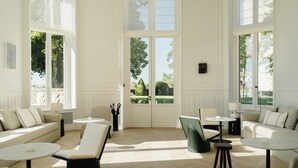 A spacious room with a large window, a sofa, a chair, and a small table. - Les Hauts de Sancerre   (Sancerre)