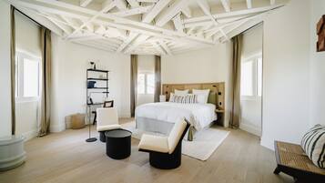 Un dormitorio con una cama grande, una silla, una mesita y una estantería.