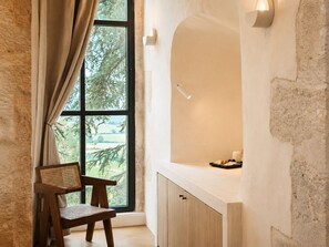 A room with a large window, a wooden chair, a white counter, and a wall-mounted light fixture.