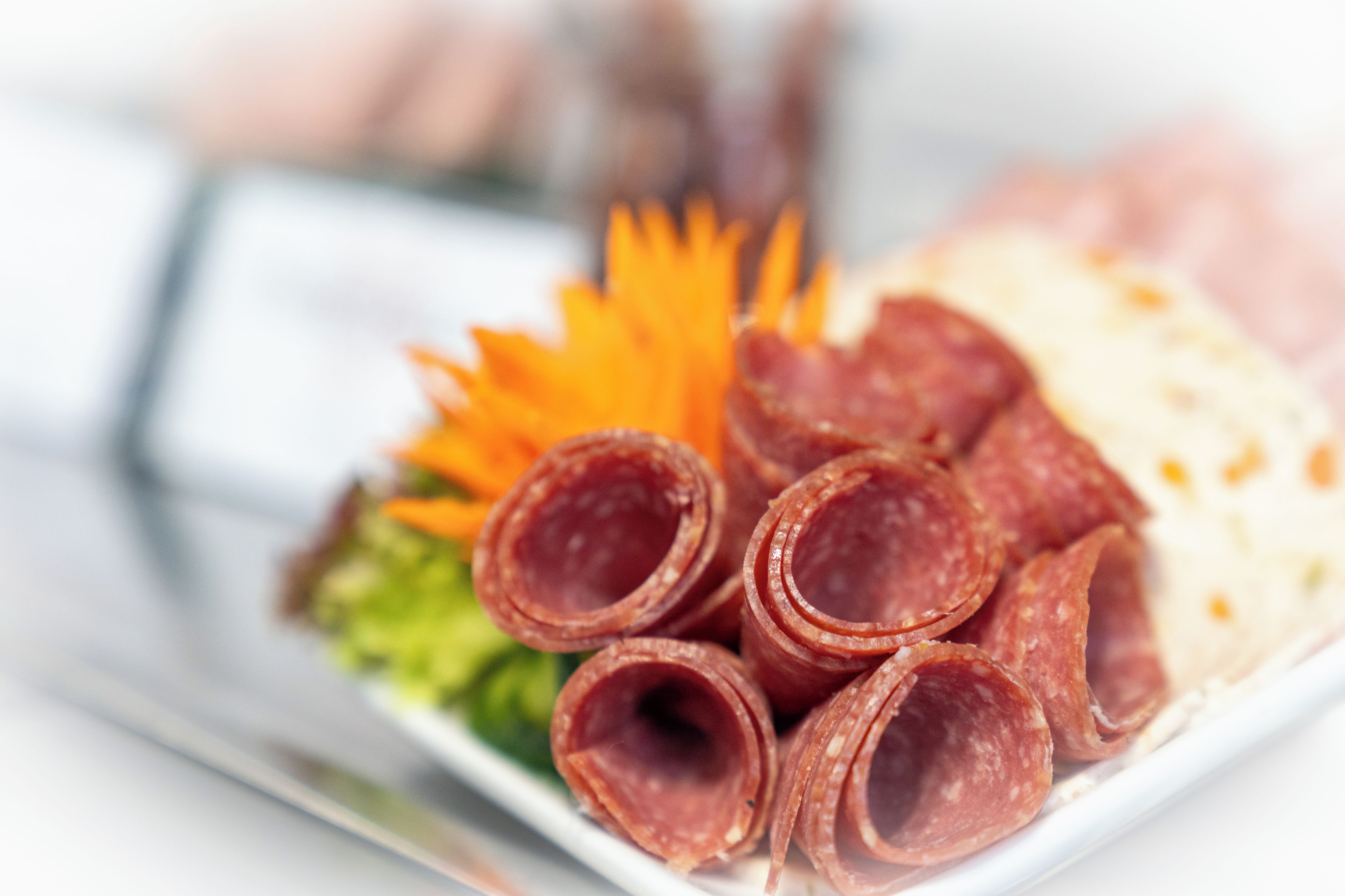 A plate with sliced meats, a garnish, and a side dish.