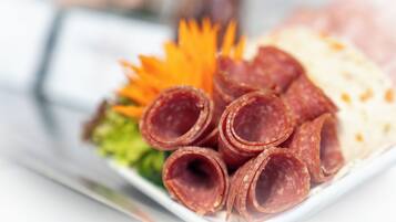 A plate with sliced meats, a garnish, and a side dish.