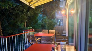 An outdoor patio with a red table and chairs, surrounded by a wooden fence and trees. - Burghotel - das Original (Nuremberg)