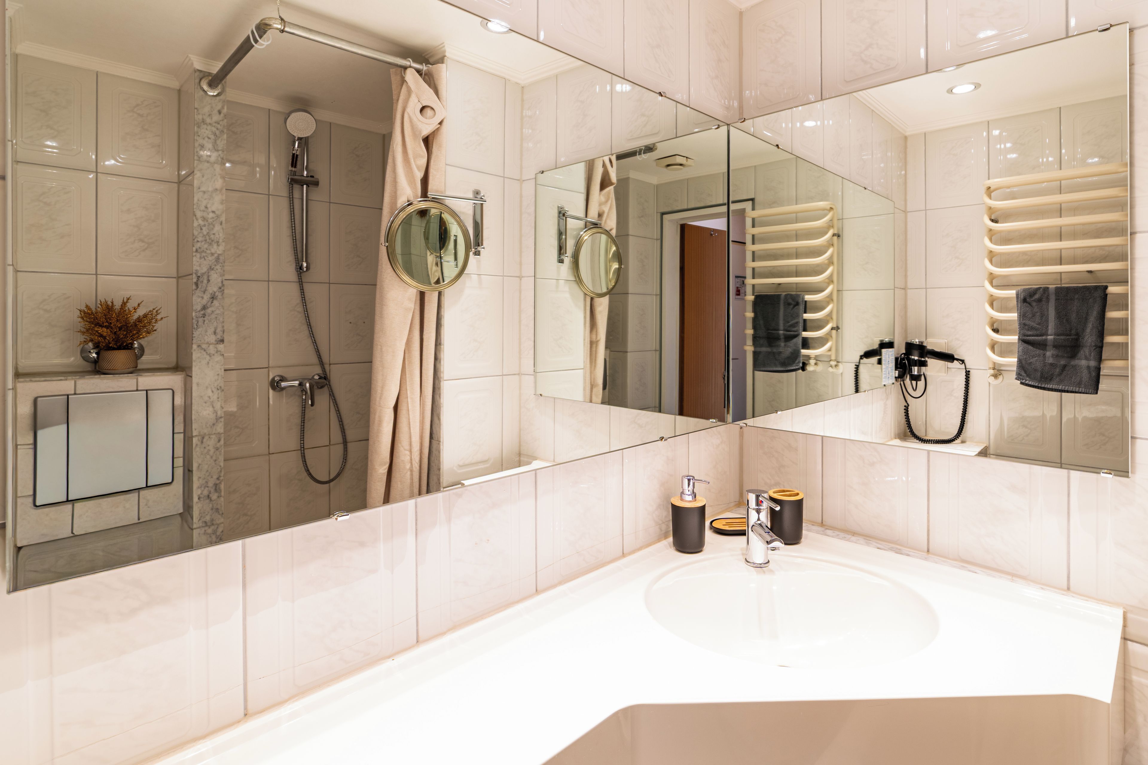 Ein modernes Badezimmer mit Dusche, Waschbecken, Spiegel und Handtuchhalter.