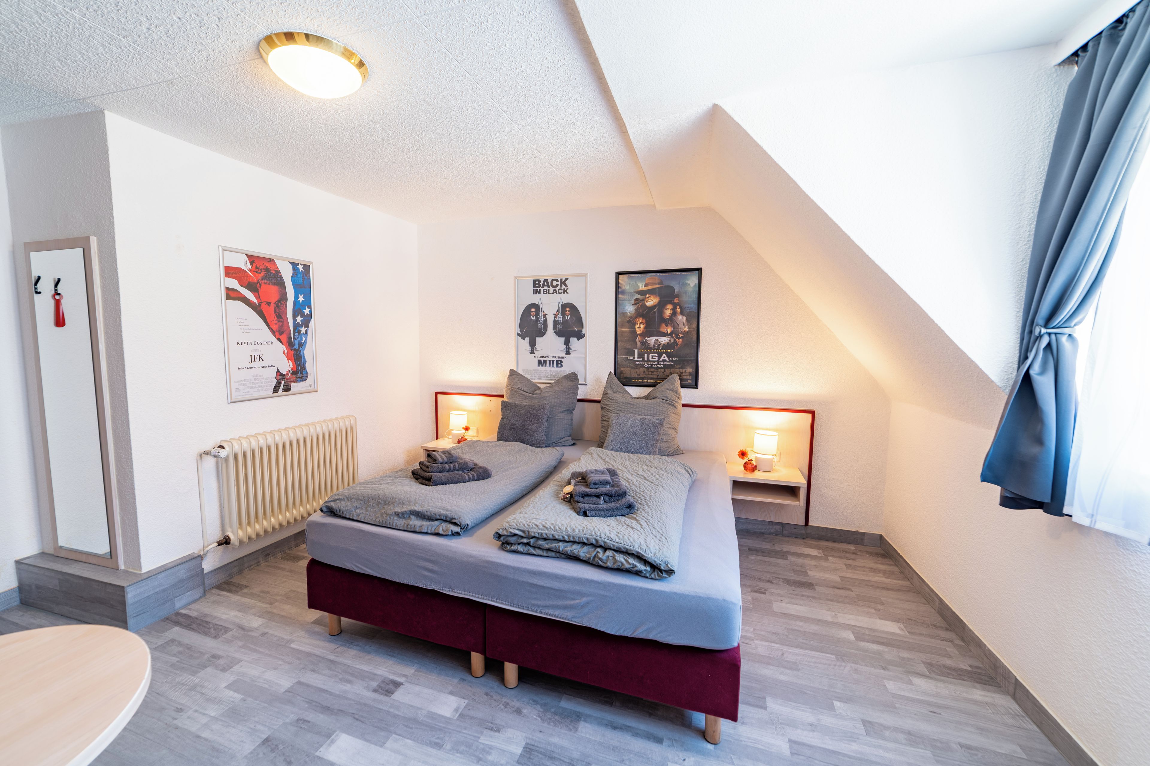 Un dormitorio moderno con techo estilo loft, una cama doble, dos mesitas de noche con lámparas y un radiador.