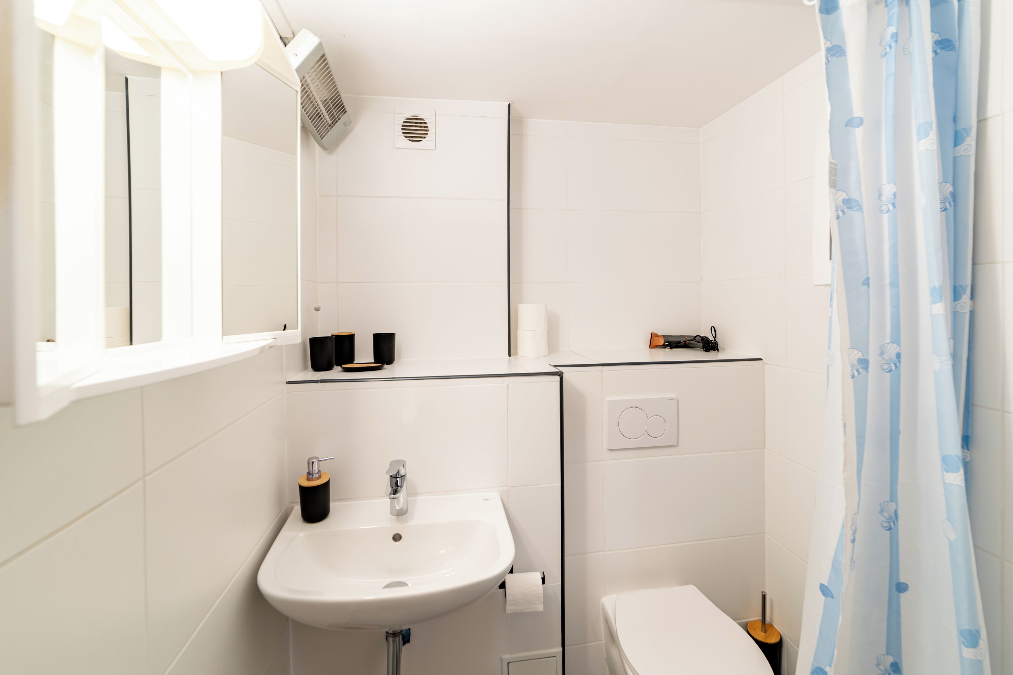 Une salle de bain avec un lavabo blanc, des toilettes et un espace douche.