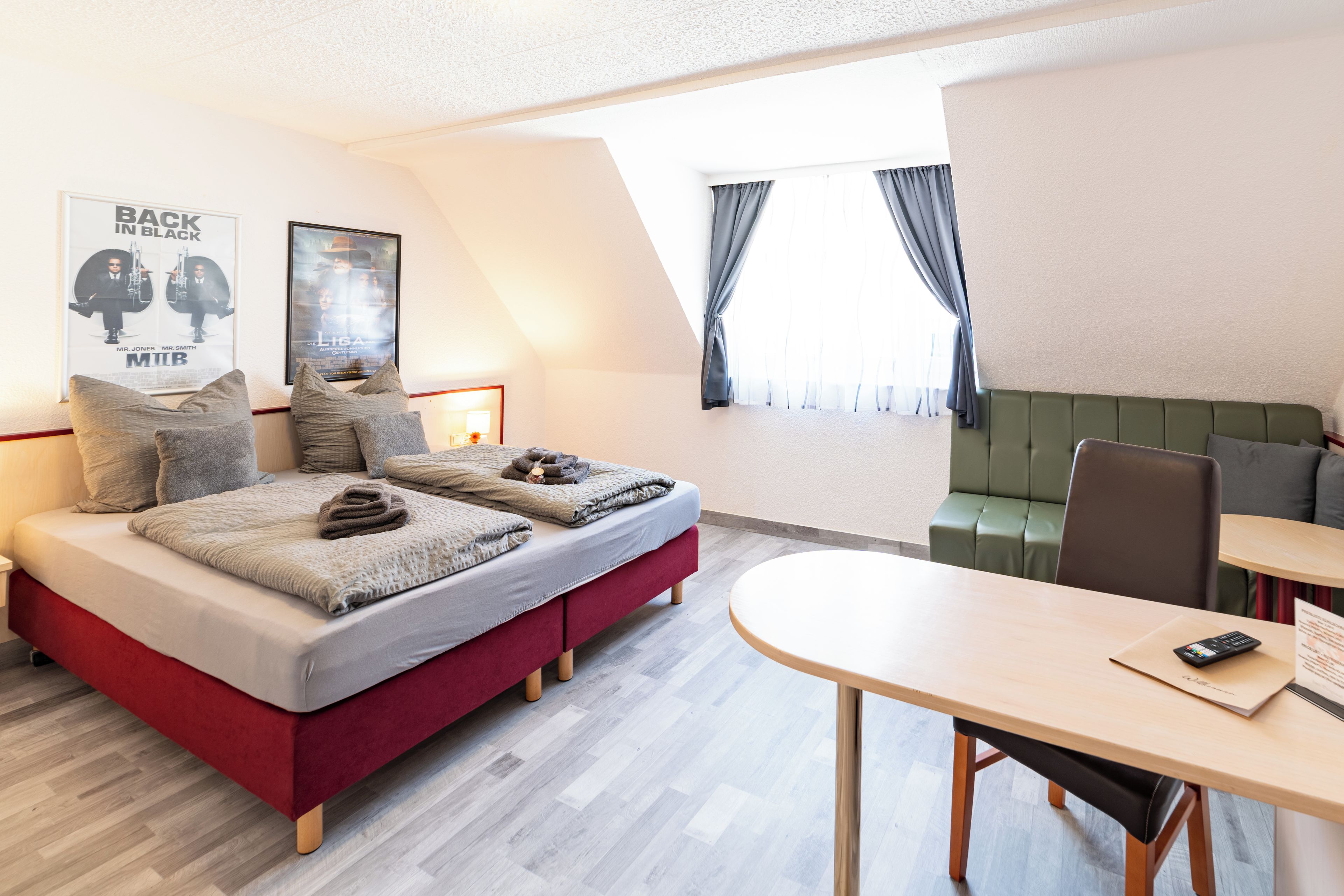 Une chambre d’hôtel moderne, équipée d’un lit, d’un bureau et offrant une vue sur l’extérieur.