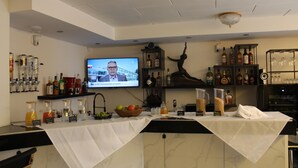 A bar area with a television screen, shelves with bottles, a fruit bowl, and a marble countertop. - Burghotel - das Original (Nuremberg)