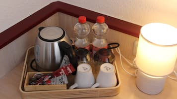 A wooden tray with a kettle, two bottles of water, a coffee maker, a cup, and a lamp.