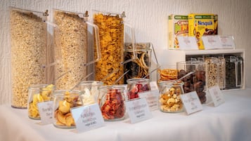A buffet with various food options including cereals, dried fruits, and nuts.