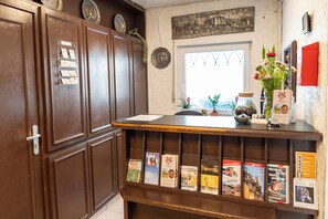 A reception desk with a wooden finish, a window with a view, and a wall-mounted clock. - Burghotel - das Original (Nuremberg)