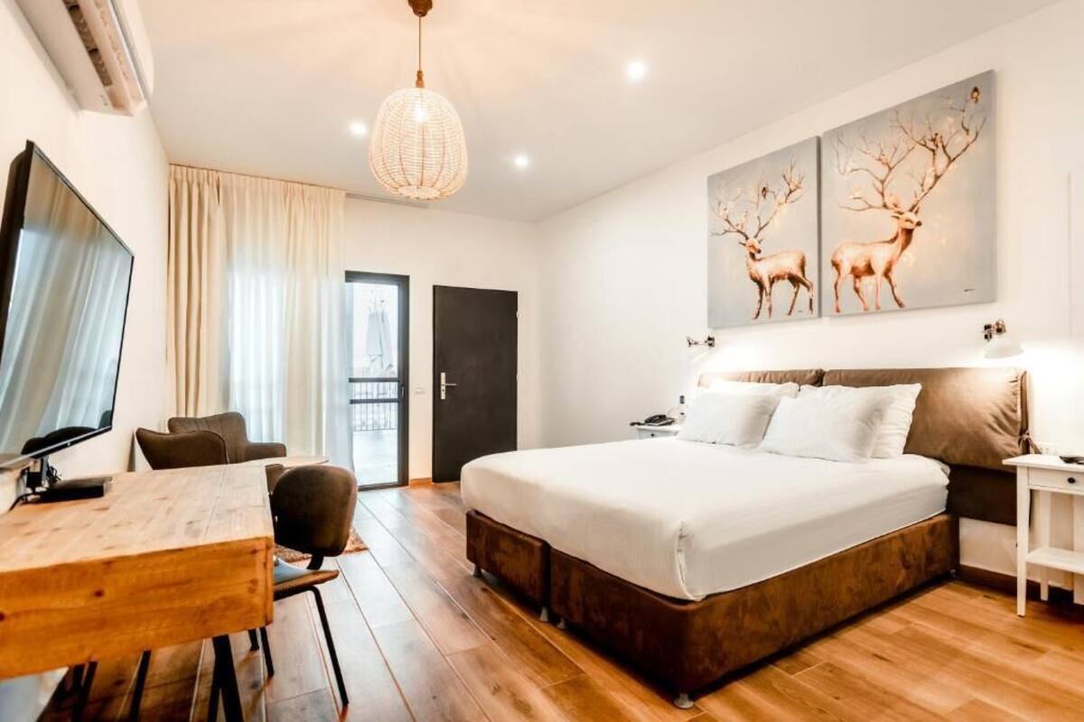 Quarto moderno com uma cama grande, soalho de madeira, uma escrivaninha e uma televisão.
