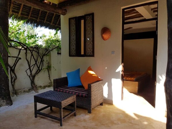 A wicker sofa with cushions, a small table, and a wall-mounted decorative item.
