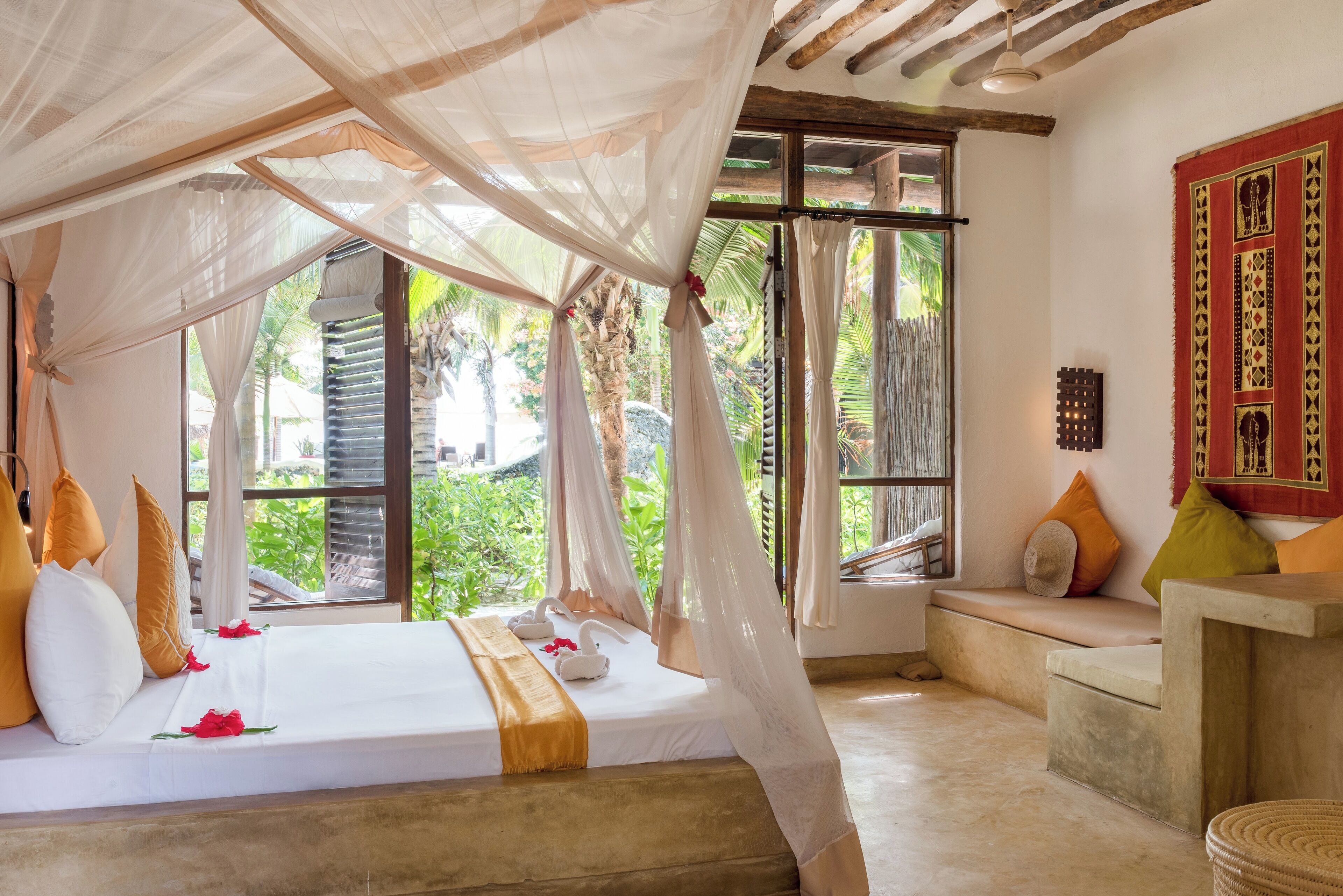 Una habitación con una cama, un banco y un ventanal grande.