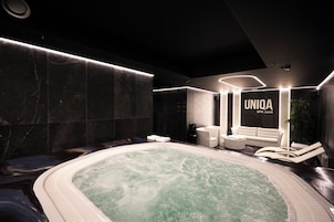 Un área de spa con un jacuzzi, sillas de descanso y un sofá.