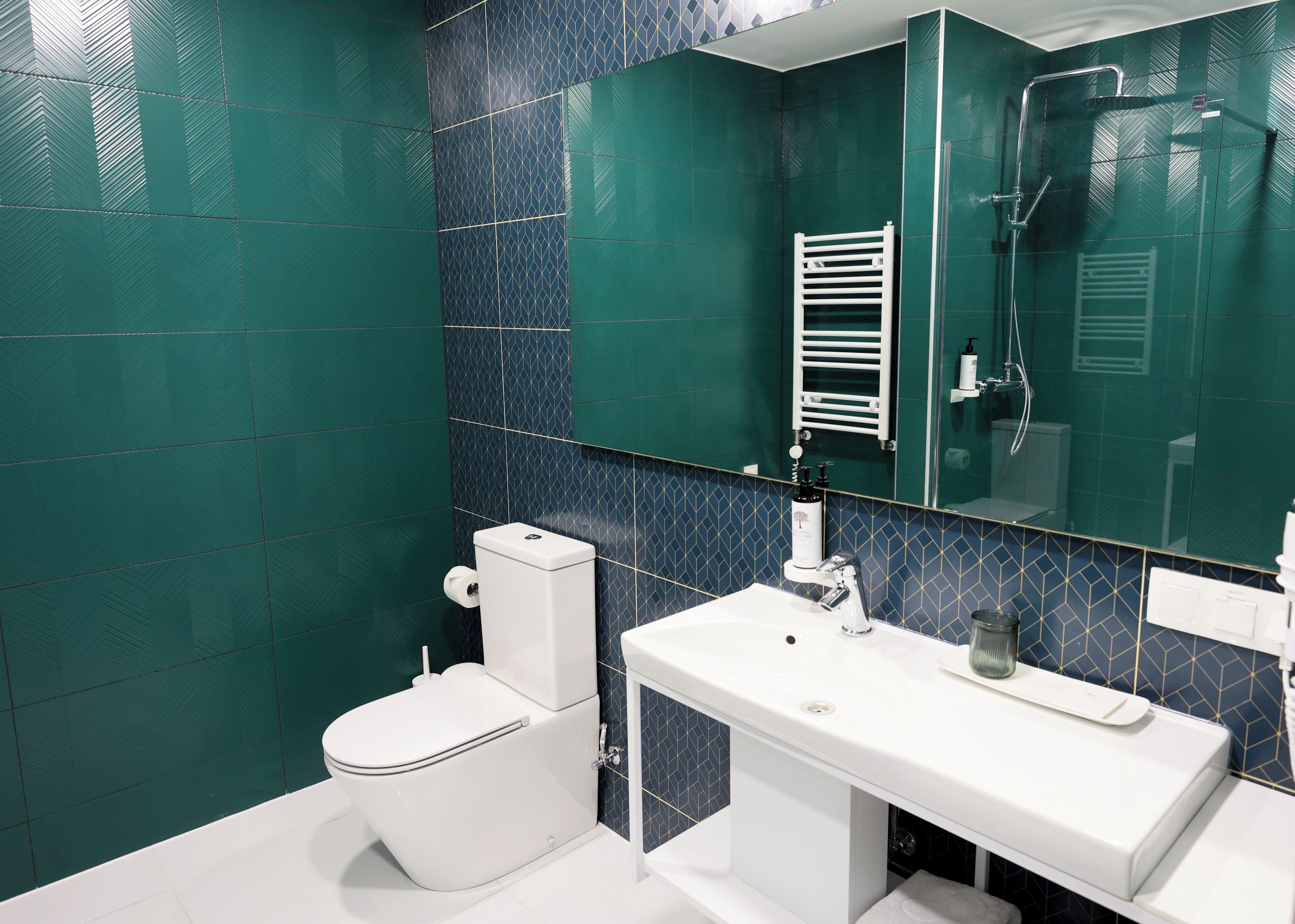 A modern bathroom with a white toilet, a sink with a mirror, and a shower area.