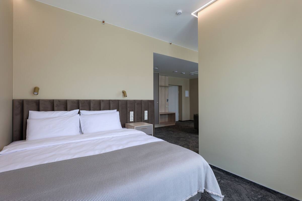 Ein Hotelzimmer mit einem großen Bett, einem Nachttisch, einem Spiegel und einem Kleiderschrank.