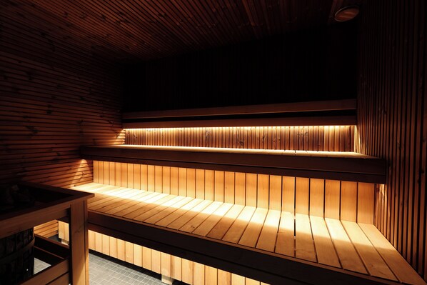 A sauna with wooden benches and a sloped ceiling. - Suncity Hotel & SPA (Šiauliai)